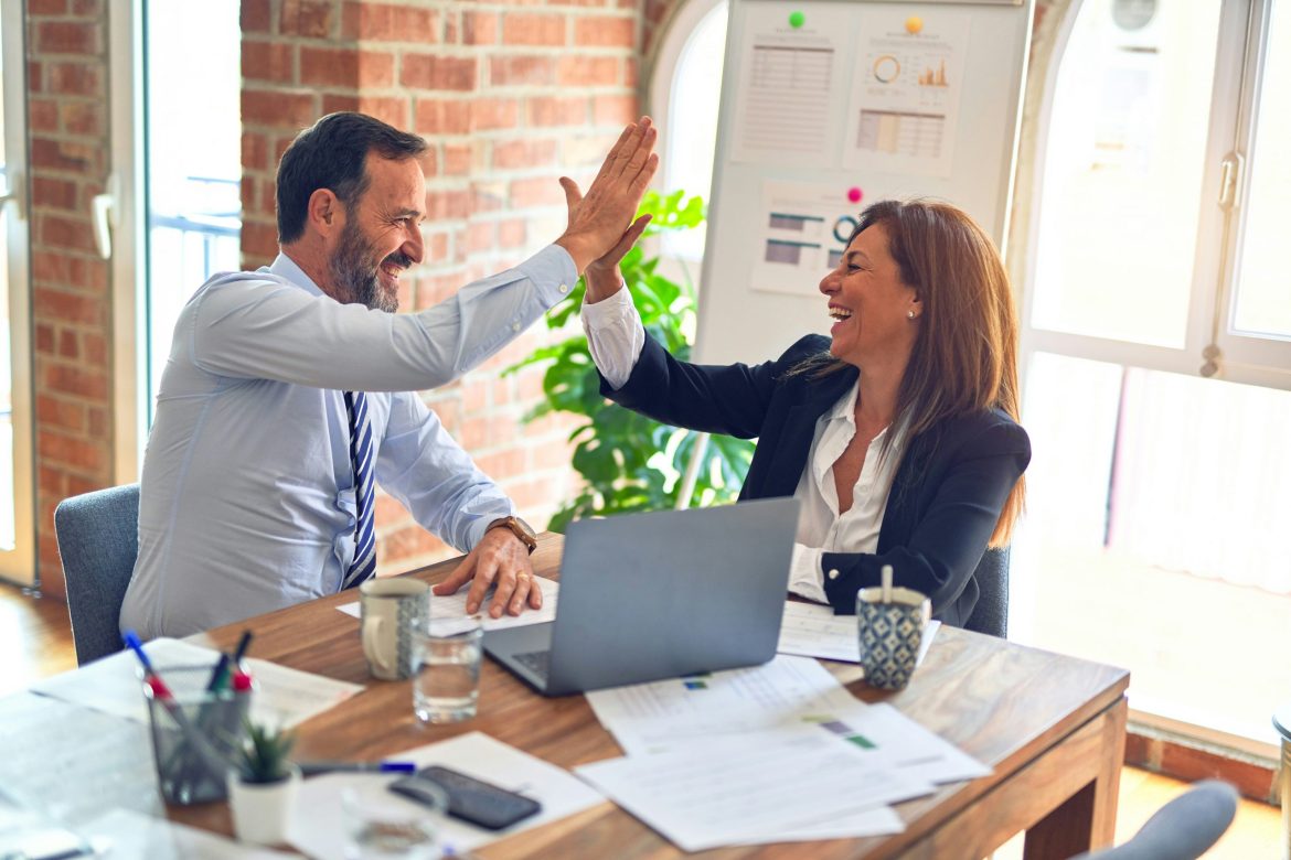 Two people in an office high fiving