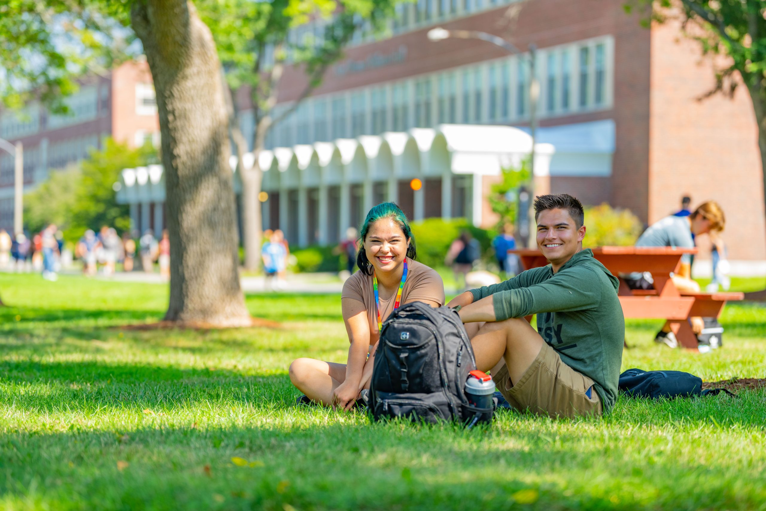 Students sitting in grass with academic building behind