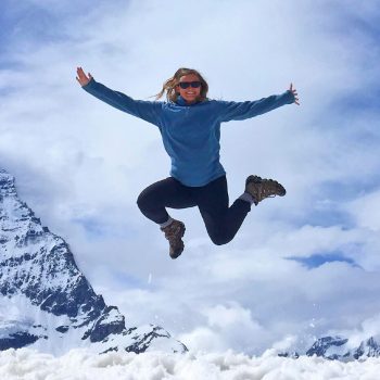 Student jumping in front of a mountain peak