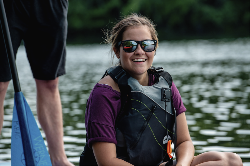 Person sitting on a paddle-board smiling at the camera