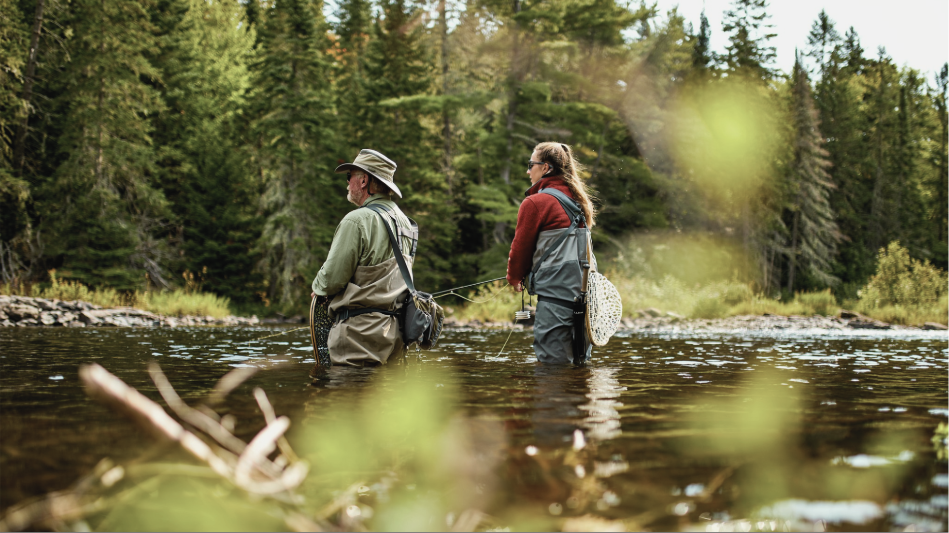 Man and woman fly fishing in a river in the forest. 