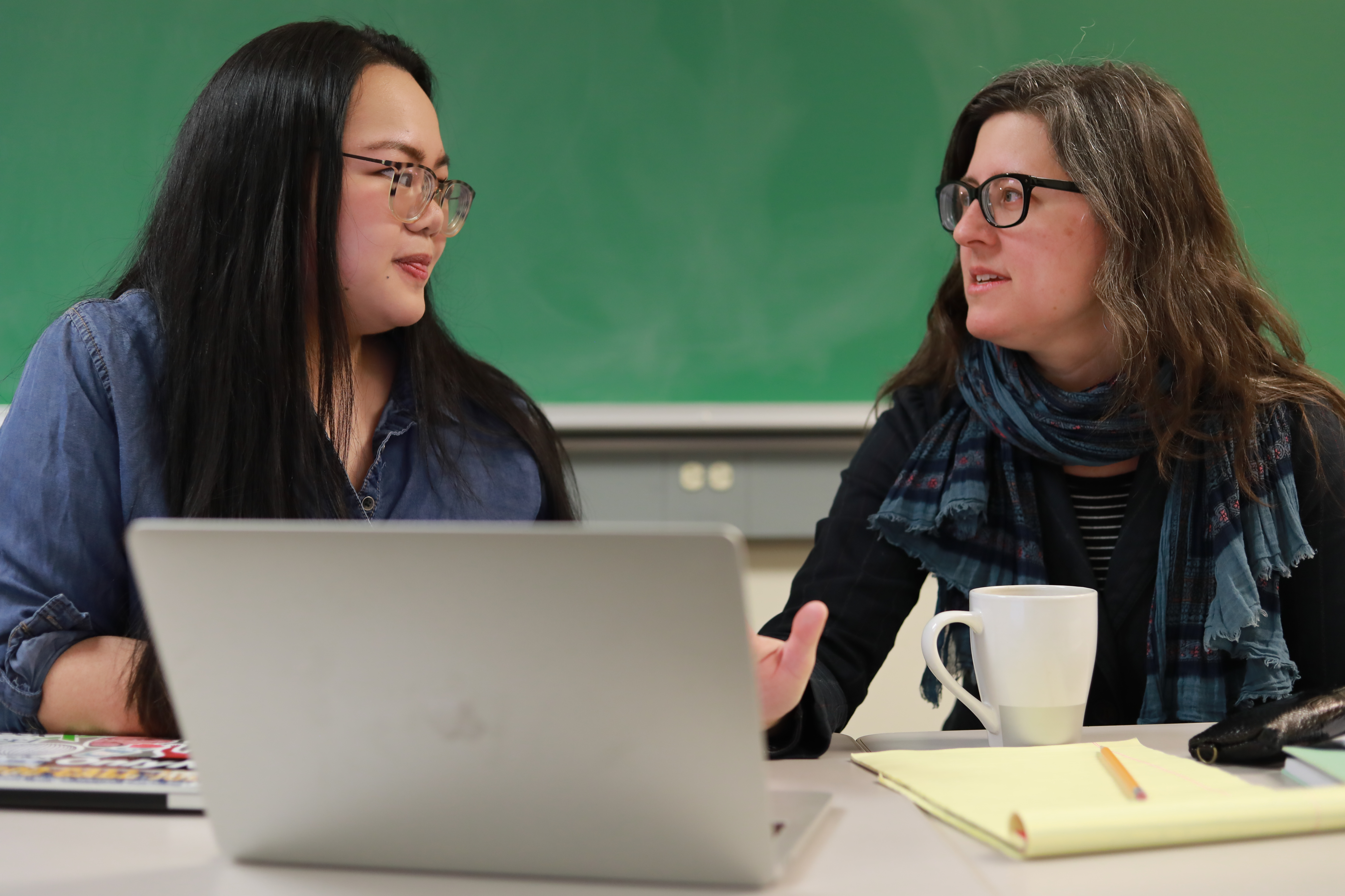 student and professor talking at a computer