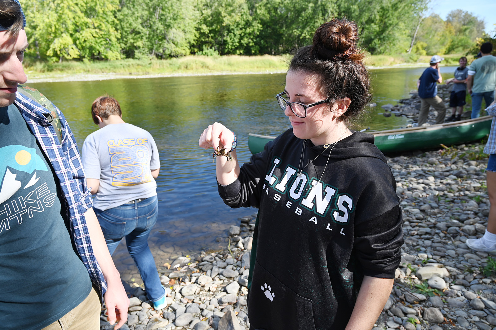 Photo of a student holding a crawfish surrounded by other students outside.